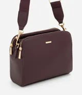 Cartera bandolera de tamaño mediano en cuero sintético color bordó, con formato rectangular y múltiples compartimentos con cierre de cremallera. Incluye correa de hombro ajustable en grosgrain y herrajes metálicos dorados.