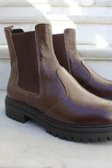 Bota tipo chelsea de cuero color chocolate, con paneles laterales elásticos y suela track de goma negra.