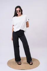 Pantalón wide leg de tiro alto confeccionado en denim negro, adornado con brillos de strass distribuidos por todo el frente.