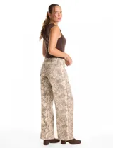 Jean de corte wide leg con estampado animal print de serpiente en tonos beige y gris. Presenta diseño clásico de cinco bolsillos, presillas para cinturón y cierre frontal con botón metálico.