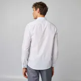 Camisa blanca de corte recto con estampado de lunares negros, cuello clásico y cierre frontal con botones.