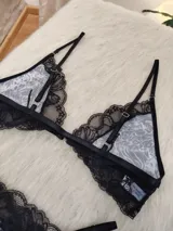 Conjunto de lencería compuesto por corpiño triangular y bombacha tipo tanga. El diseño combina microtul con estampado animal print y detalles de encaje negro en los bordes. El corpiño cuenta con cierre frontal y breteles regulables.