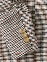 Blazer de mujer con estampado pata de gallo en tonos beige, negro y marrón. Presenta solapas de muesca, un solo botón dorado al frente y mangas largas con efecto fruncido.