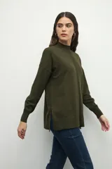 Polera negra de manga larga con puños elastizados, cuello alto y sutiles aberturas en los laterales.