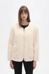 Chaqueta de pana color natural, con cuello a la base, cierre frontal y bolsillos delanteros tipo parche. Diseño holgado de manga larga.