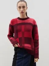 Sweater de punto con diseño jacquard a cuadros en tonos azul, marrón, crema y negro. Presenta cuello redondo, puños y ruedo acanalados, con un corte holgado y cómodo.
