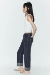 Pantalón de jean de tiro medio con corte recto y cinco bolsillos. Presenta un acabado con dobladillo ancho en el bajo y cierre frontal con botones metálicos.
