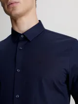 Camisa azul marino de popelín de algodón elástico, corte slim, con cierre frontal de botones y logo bordado en el pecho.