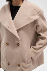 Tapado corto de paño en color beige, con cuello solapa amplio y cierre frontal cruzado con doble botonadura. Presenta mangas largas y bolsillos laterales integrados.