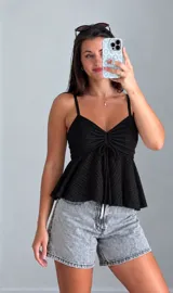 Musculosa de encaje negro con tirantes finos, escote en V con cordón ajustable en el centro y diseño con volados en la parte inferior.