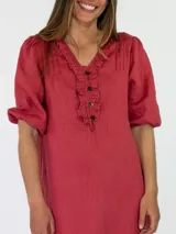 Vestido largo de lino color marrón tostado, con mangas 3/4 abullonadas, escote en V con volados y botones frontales. Cuenta con bolsillos laterales y detalle de volado en el dobladillo inferior.