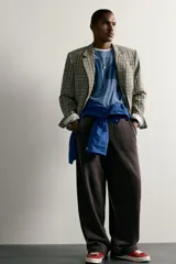 Blazer de corte boxy fit de Zara, confeccionado en tejido con algodón con estampado a cuadros en tonos beige, negro y blanco. Cuenta con cuello de solapas de muesca, manga larga con botones en los puños, bolsillos de vivo en el pecho y de plastrón en la cadera, y cierre frontal con un botón.