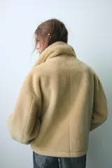 Cazadora reversible de cuello subido y manga larga, con bolsillos de vivo en el delantero y cierre frontal con botones. Confeccionada en tejido combinado con efecto pelo y efecto ante.