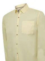 Camisa de manga larga RKF modelo Galiton, color amarillo, confeccionada en popelina 100% algodón orgánico. Cuenta con cuello camisero, botones de madera, un bolsillo frontal en el pecho con logo bordado y mangas ajustables.