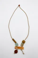 Collar largo de cordón beige con cuentas geométricas colgantes de piedra y madera en tonos marrón, naranja y celeste.