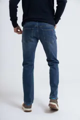 Pantalón de jean azul de corte slim, con diseño clásico de cinco bolsillos, trabillas para cinturón y cierre frontal con botón y cremallera.