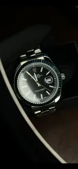Reloj de pulsera Rolex Datejust con esfera negra, bisel estriado, brazalete metálico plateado tipo jubilee y función de calendario con lupa.