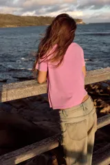 Remera de algodón color rosado con efecto lavado, de corte regular y cuello redondo, con texto rojo estampado en el frente que dice 'CENTER OF ATTENTION'.