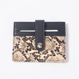 Tarjetero de cuero sintético con diseño combinado en color negro y estampado animal print de serpiente, con tira con botón a presión y ranuras para tarjetas.