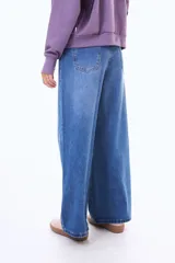 Jean de corte wide leg en color azul medio con efecto lavado. Presenta tiro medio, cierre frontal con botón y bolsillos laterales y traseros.