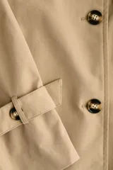 Gabardina midi de doble botonadura con diseño oversized, solapas de muesca, cierre frontal con botones y cinturón extraíble para atar en la cintura. Presenta mangas raglán con trabillas ajustables en los puños, bolsillos laterales y abertura posterior.