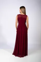 Vestido largo de fiesta color bordó, con escote redondo y detalle de encaje en la parte superior. Presenta una falda con tablas que aporta movimiento y caída fluida.