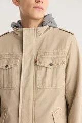 Campera color beige con capucha gris, cierre frontal con cremallera y botones a presión, cuatro bolsillos frontales con solapa y charreteras en los hombros.