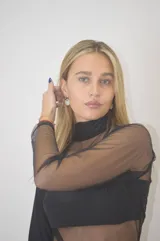 Vestido corto negro con cuello alto, mangas largas de tul y transparencias en el torso y abdomen.