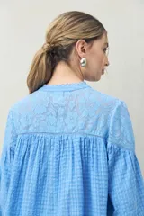 Blusa blanca de algodón con encaje floral en la parte superior, mangas largas abullonadas y escote con lazo.