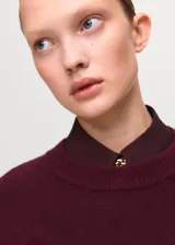 Sweater de punto medio color bordó, de silueta recta, manga larga y cuello redondo.