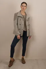 Chaqueta corta de lana color beige con diseño de espiga, doble abotonadura, cuello solapa y bolsillos ojal. Presenta apliques de tela en los hombros.