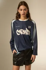 Remera de manga larga estilo deportivo, confeccionada en tejido técnico. Presenta un diseño color block en azul marino y celeste, con cuello redondo y estampado gráfico frontal en color blanco.