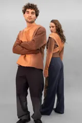 Buzo de lana merino afieltrada color negro con estampado abstracto plateado en el frente. Tiene cuello redondo y puños con forma que cubre levemente la mano. Es más largo en la parte inferior trasera.