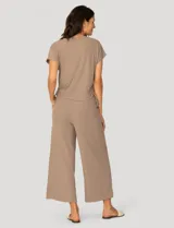 Conjunto de dos piezas compuesto por una remera de manga corta con cuello redondo y frunces laterales ajustables, y un pantalón de corte ancho con cintura elástica y bolsillos laterales.