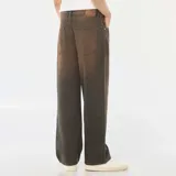 Pantalón de jean con corte baggy y pierna ancha, con efecto de lavado vintage en tono marrón oscuro. Cuenta con diseño clásico de cinco bolsillos, cierre frontal con botón y trabillas para cinturón.