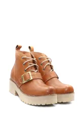 Borcego de cuero color beige con cordones, suela track de goma y detalle de hebilla metálica en el empeine.