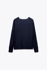 Jersey de punto liso, color azul brillante, con cuello redondo y manga larga. Presenta acabados en rib en puños, cuello y bajo, con aberturas laterales en el ruedo.