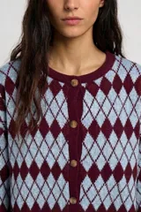 Saco tejido con cierre frontal de botones, cuello redondo y mangas largas. Presenta un diseño de patrón de rombos en tonos celeste y bordó.