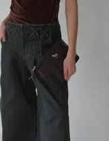 Sobre tipo cartuchera de lona con estampado de camuflaje y terminaciones en cuero marrón.