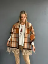 Ruana abierta con diseño de cuadros en tonos tierra, naranja y beige, con terminación de flecos en el ruedo.