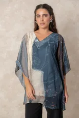 Blusa tipo túnica de gasa semitransparente con escote en V. Presenta un diseño fluido con estampado artístico en tonos azules, blancos y detalles rojizos, y mangas amplias tipo kimono.