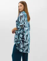 Conjunto de tres piezas compuesto por una musculosa de escote redondo, un saco largo abierto de mangas 3/4 y un pantalón palazzo de pierna ancha. La musculosa y el saco presentan un estampado abstracto de pinceladas en tonos azules con hilos metalizados, mientras que el pantalón es de color azul petróleo liso.