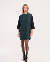 Vestido corto negro con mangas 3/4 verdes, cuello bote y bolsillos laterales.