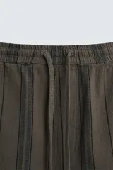 Bermuda de algodón color blanco, de corte relajado (relaxed fit), con cintura elástica ajustable mediante cordón. Posee bolsillos laterales y un bolsillo trasero de plastrón. Presenta un bordado en contraste en la pernera.