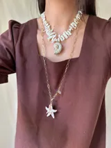 Collar corto con cuentas irregulares de nácar color blanco y dije de caracol con detalles dorados. Cierre con gancho y cadena de acero quirúrgico para regular el largo.