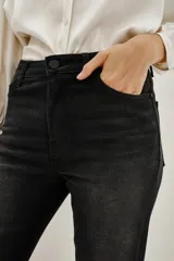 Jean negro de tiro medio, ajustado en la cintura y que se ensancha sutilmente desde la cadera al ruedo, formando un acampanado. Confeccionado en tejido con elastano, lavado stone, localizado y con bigotes. Los bolsillos traseros llevan un bordado de alas.