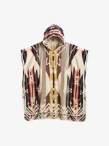 Toalla tipo poncho con capucha, confeccionada en tejido jacquard de algodón ultrasuave, con exterior aterciopelado y bucles absorbentes en el interior. Presenta un estampado geométrico en tonos tierra, beige, azul oscuro y rojizo.