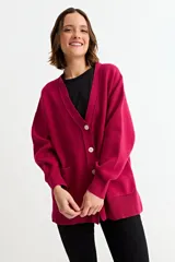 Cardigan de punto color fucsia, con cuello en V, cierre frontal con botones y bolsillos laterales. Presenta un diseño holgado con mangas largas y puños acanalados.