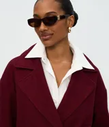 Abrigo corto tipo blazer de color bordó con estampa de espiga, cuello con solapas, cierre cruzado con dos botones y bolsillos ribeteados.