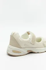 Zapatillas deportivas negras con suela blanca de 4cm de alto y tira ajustable con velcro.